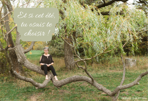 Claudine est assise paisiblement sur une branche d’arbre courbée, entourée d’un feuillage vert tendre, dans un environnement naturel apaisant. Le message « Et si cet été, tu osais te choisir ! » est inscrit en lettres blanches dans un encadré vert doux en haut à gauche. L’image inspire la sérénité, le recentrage sur soi et l’invitation à prendre du temps pour soi.