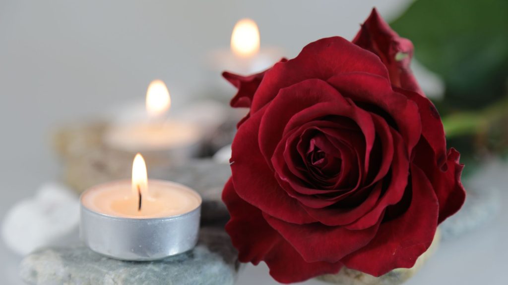 Rose rouge et bougies allumées symbolisant le recueillement et la paix intérieure. Image illustrant le coaching en deuil avec Claudine Blier, coach spécialisée en traversée du deuil et désencombrement émotionnel.