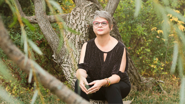 Claudine Blier, spécialisée en traversée du deuil et désencombrement émotionnel, assise dans un arbre en pleine nature, symbole des empreintes invisibles laissées par les épreuves.