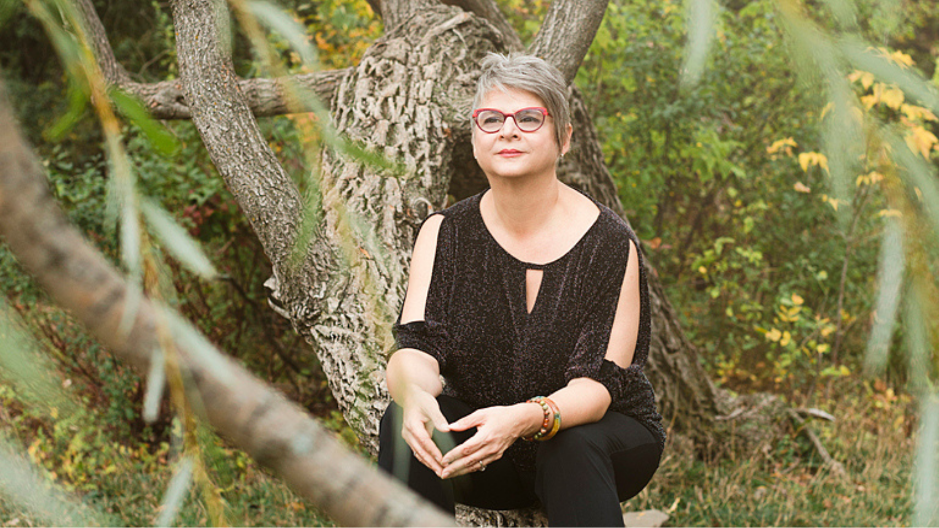 Claudine Blier, spécialisée en traversée du deuil et désencombrement émotionnel, assise dans un arbre en pleine nature, symbole des empreintes invisibles laissées par les épreuves.