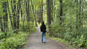 Une femme marche seule sur un sentier en forêt, dans un moment de retour vers soi.
